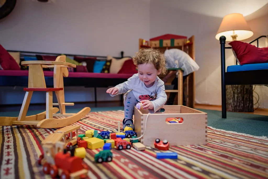 Kind spielt im großen Raum mit Spielsachen
