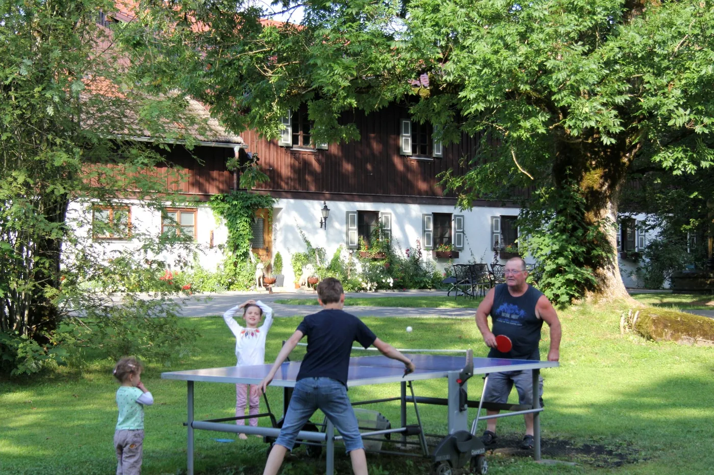 Familie spielt Tischtennis vor dem Gutshaus