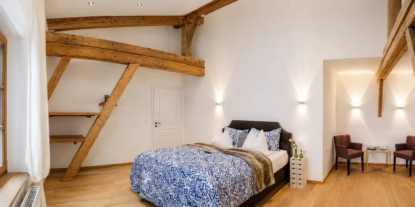 Panoramablick auf das großzügige Schlafzimmer im Kleinen Apartment II mit Doppelbett und historischen Holzbalken