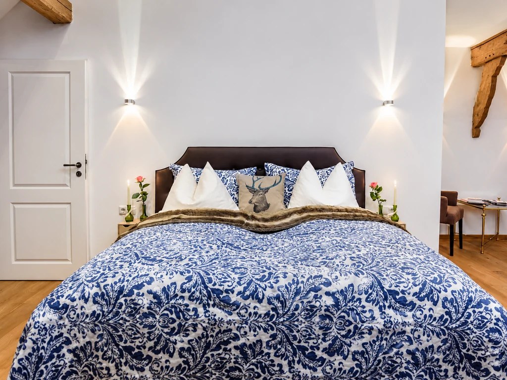 Großes Doppelbett im Kleinen Apartment II mit blau-weißer Tagesdecke und historischen Holzbalken