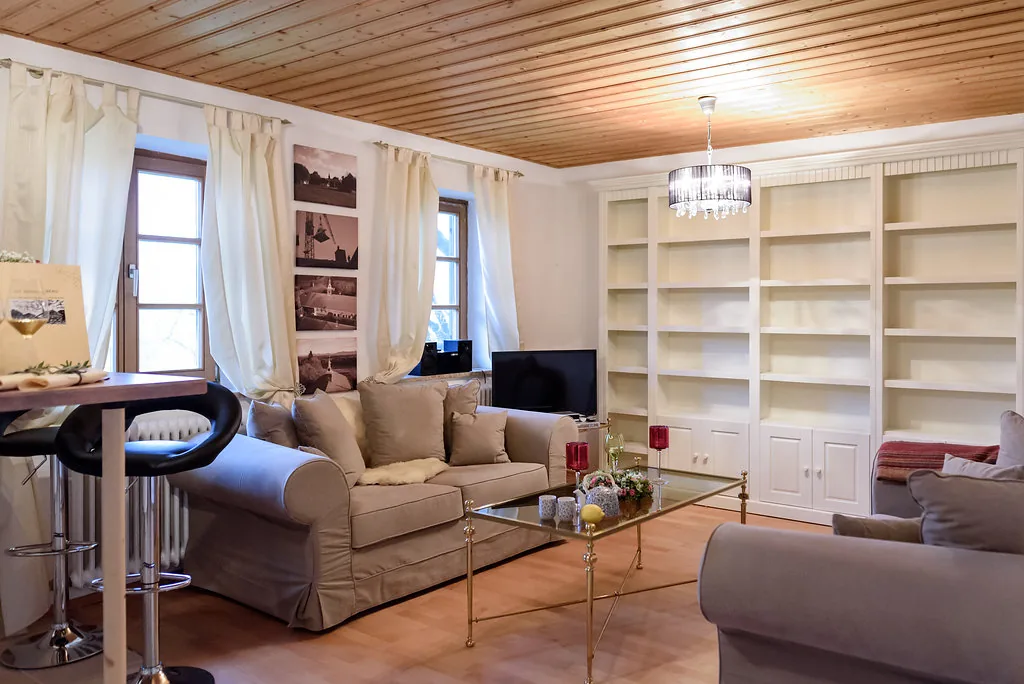 Heller Wohnbereich im Kleinen Apartment II mit Sofa, Fenstern und Einbauregal